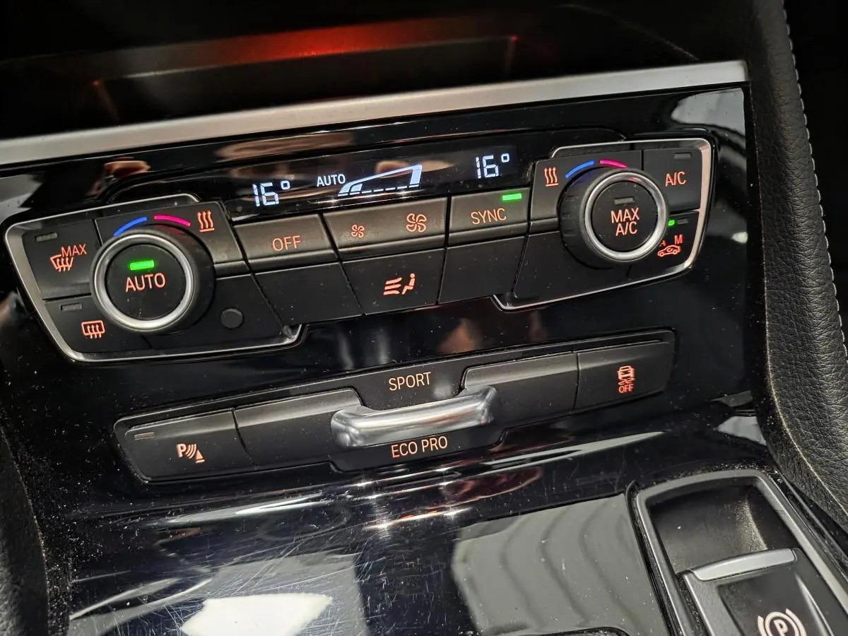 Détail de la console centrale noire brillante avec commandes de climatisation et modes de conduite BMW Série 2 Gran Tourer.