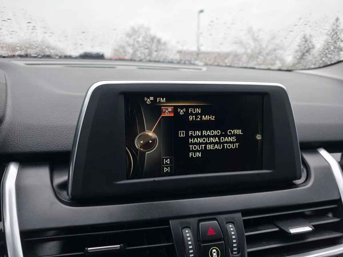 Écran central de bord affichant la radio FM dans l’habitacle d’une BMW Série 2 Gran Tourer blanche.