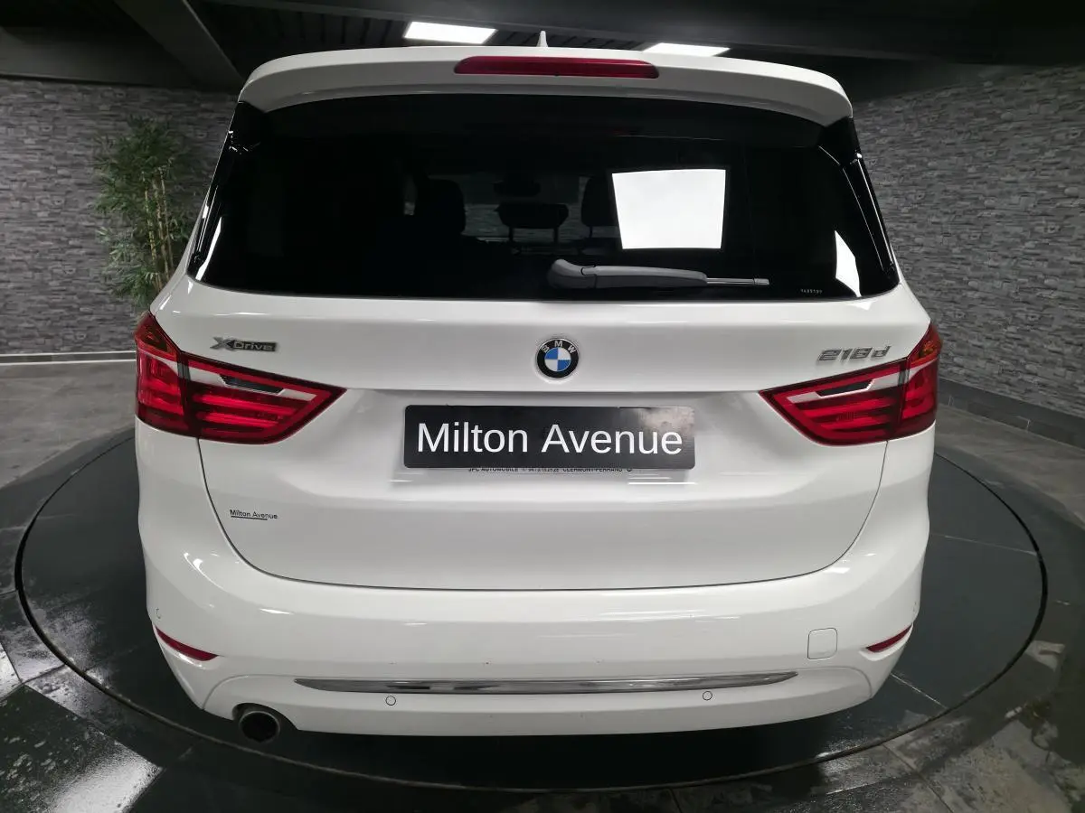 Vue arrière d'une BMW Série 2 Gran Tourer blanche avec badge xDrive et modèle 218d visible sur le hayon.