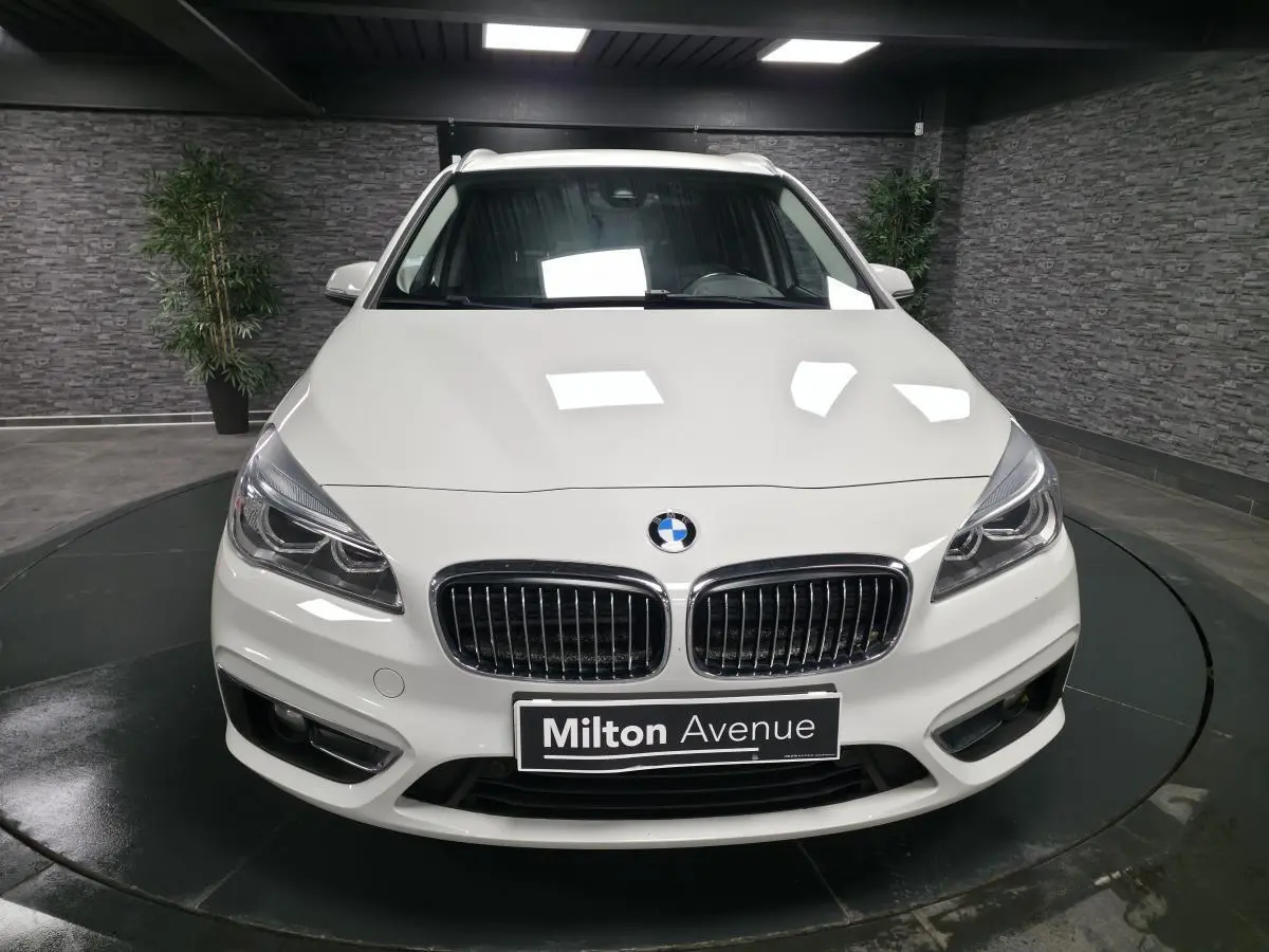 Vue avant d'une BMW Série 2 Gran Tourer blanche avec calandre chromée et phares LED dans un showroom.