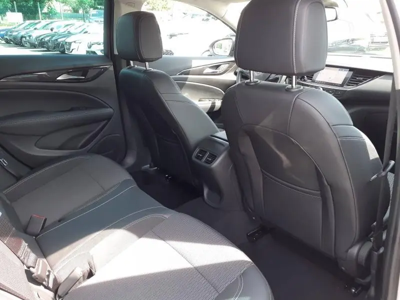 Vue intérieure arrière côté droit de l’Opel Insignia Grand Sport gris clair, sièges en tissu et cuir avec coutures contrastées.