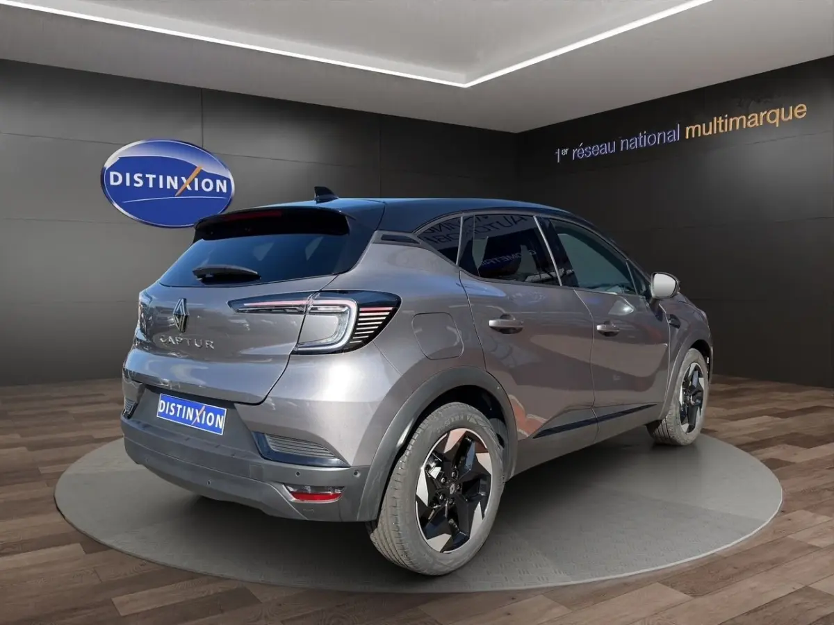 Renault Captur gris foncé en vue 3/4 arrière droit, avec jantes noires et toit noir brillant.