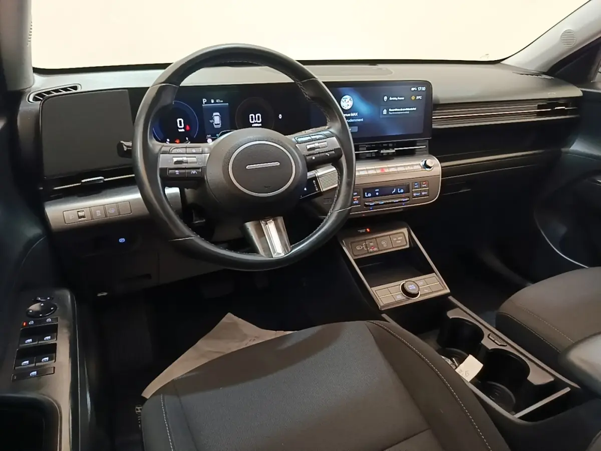 Intérieur noir de la Hyundai Kona 2024, vue depuis le siège conducteur avec volant cuir et écran tactile central.