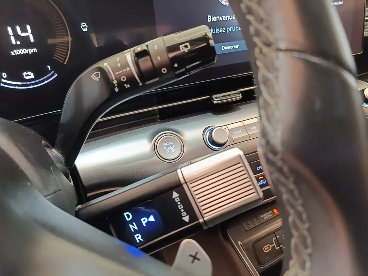 Vue rapprochée de l’intérieur du Hyundai Kona 2024 hybride, montrant le volant cuir et la commande de boîte automatique éclairée.