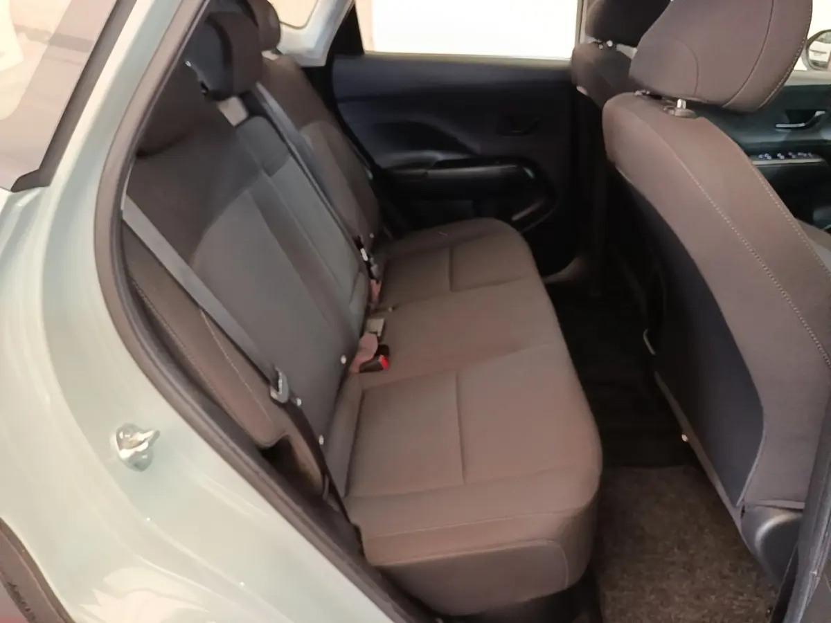 Vue intérieure côté gauche montrant la banquette arrière grise du Hyundai Kona 1.6 Hybrid 2024 vert pâle.