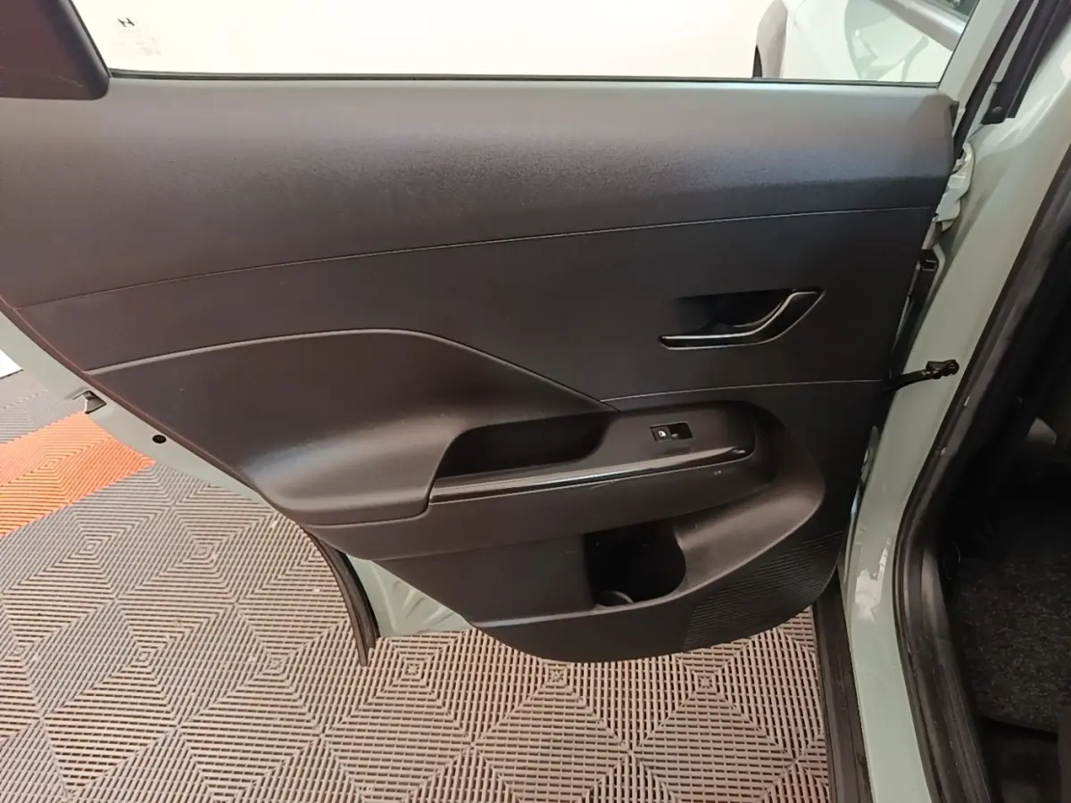 Vue intérieure sur la porte arrière gauche noire du Hyundai Kona 1.6 Hybrid 2024 vert, avec poignée et commande de vitre.