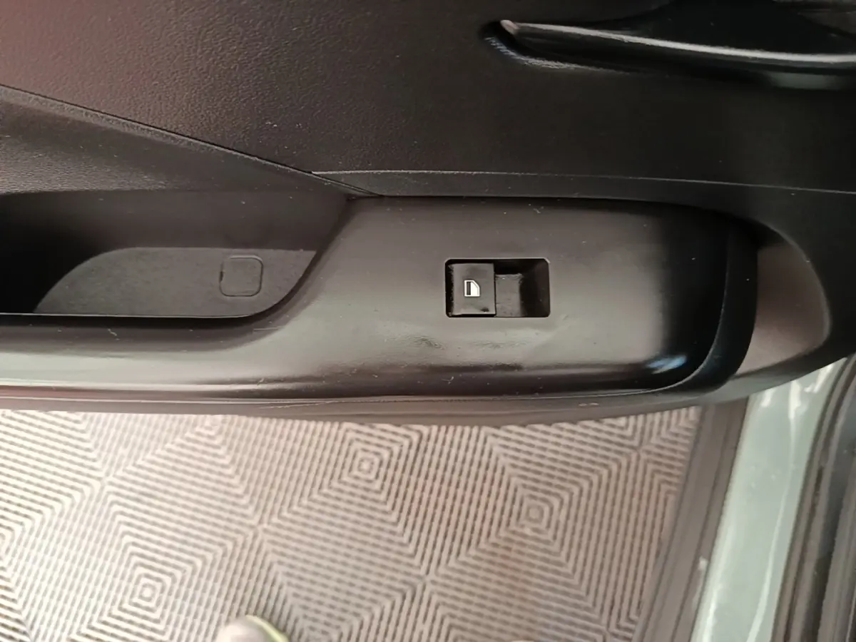 Gros plan sur le bouton de verrouillage de porte côté conducteur d’un Hyundai Kona vert 2024, intérieur noir.
