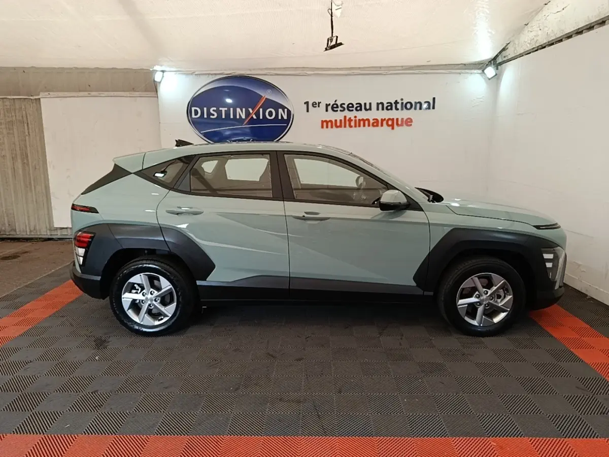 Vue de profil côté gauche d’un Hyundai Kona 2024 vert avec protections noires sur les passages de roues.