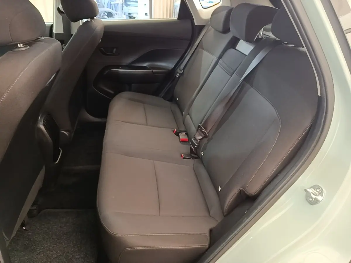 Vue intérieure côté droit montrant la banquette arrière noire du Hyundai Kona 2024 vert, avec ceinture de sécurité attachée.