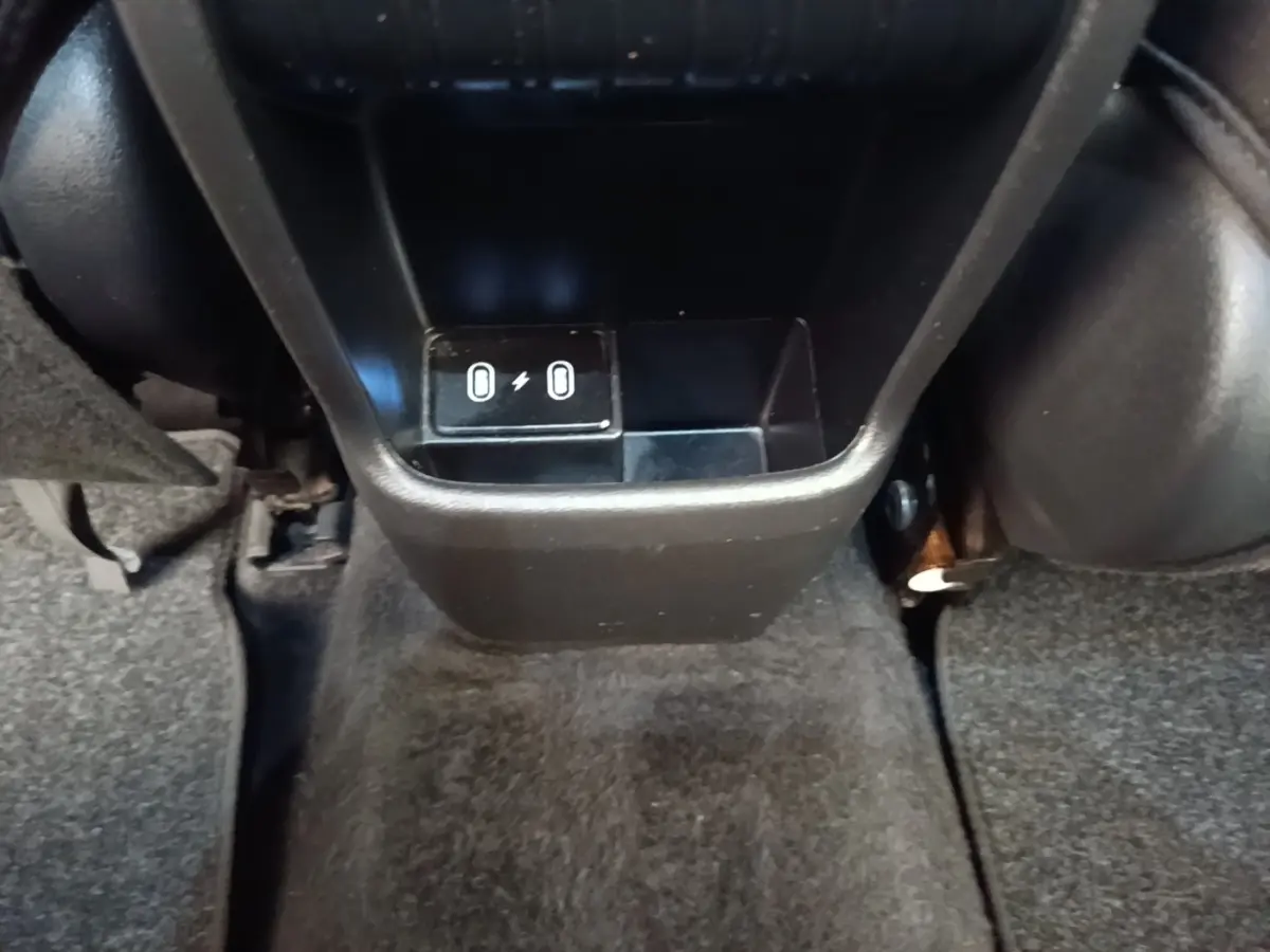 Gros plan sur la console centrale arrière noire du Hyundai Kona 1.6 Hybrid 2024 avec ports USB visibles.