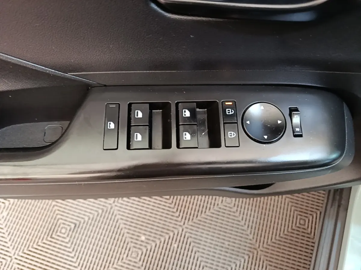 Gros plan sur les commandes de lève-vitres et rétroviseurs côté conducteur d’un Hyundai Kona vert 2024.