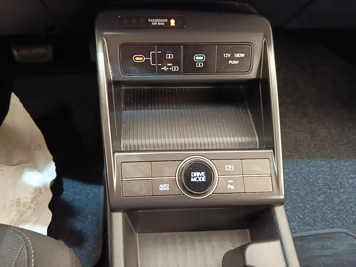 Gros plan sur la console centrale noire du Hyundai Kona 2024, avec commandes Drive Mode et ports USB visibles.