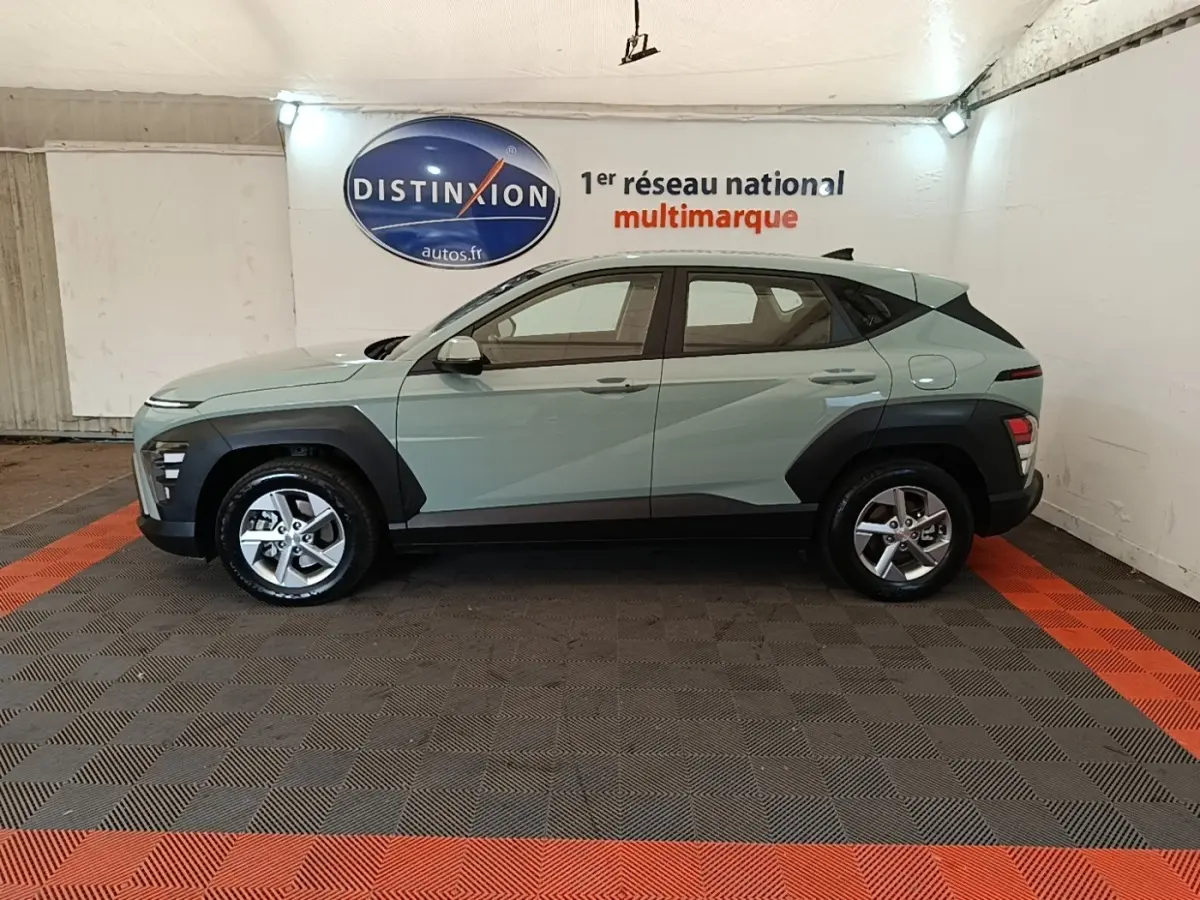 Vue de profil côté gauche d'un Hyundai Kona 2024 vert avec protections noires et jantes alliage cinq branches.
