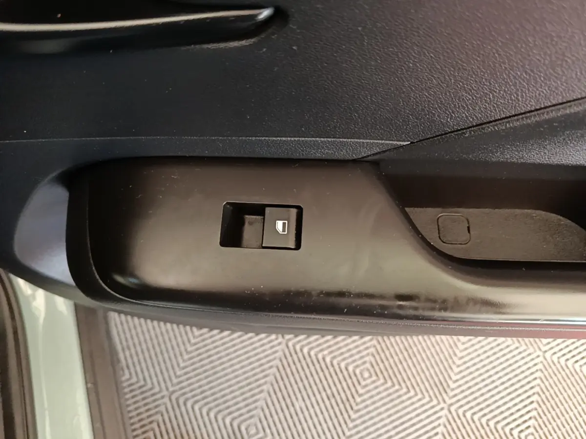 Gros plan sur le bouton de commande de vitre électrique côté conducteur dans une Hyundai Kona 1.6 Hybrid 2024 vert.