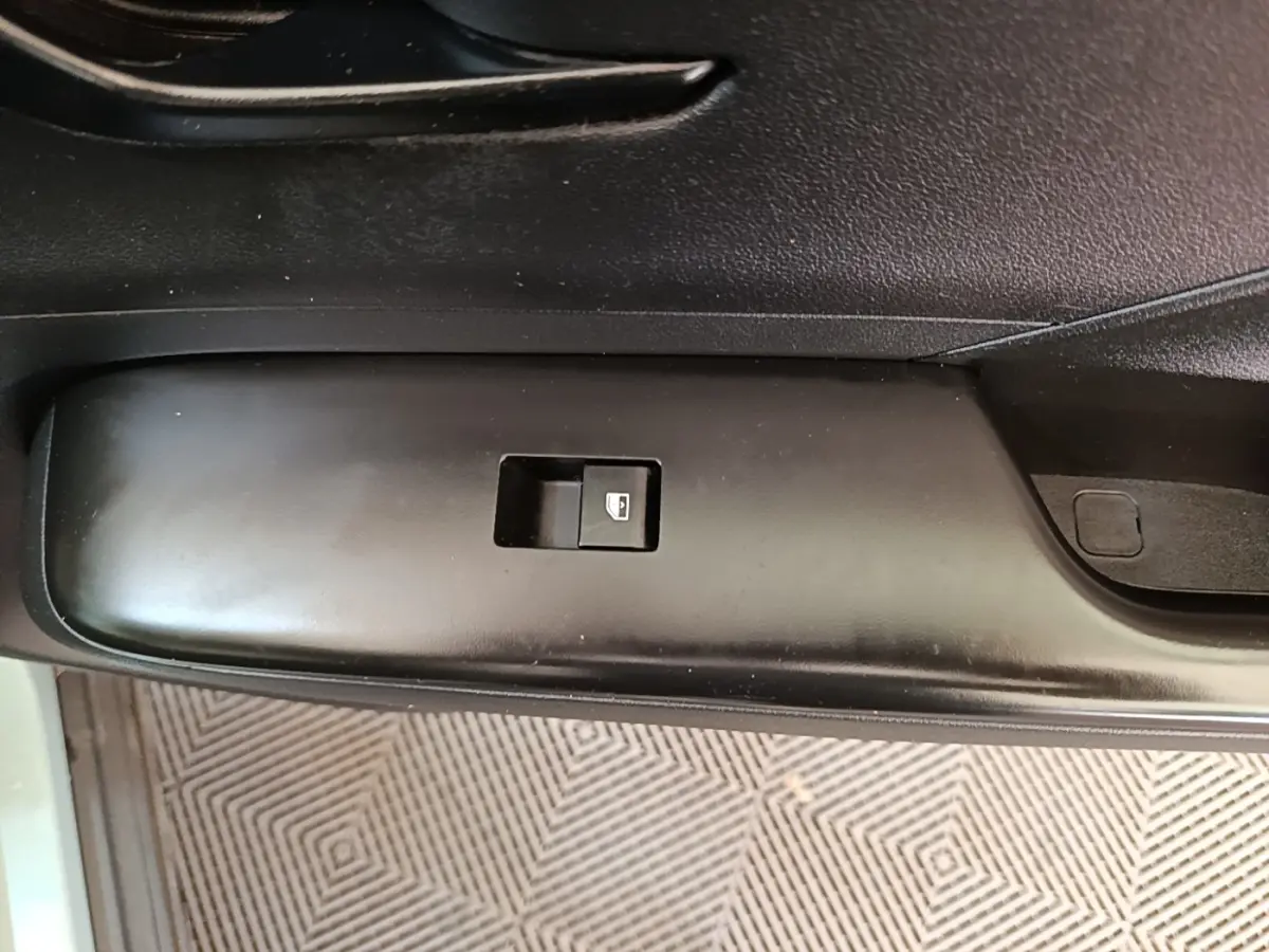 Gros plan sur le bouton de commande de la vitre électrique côté conducteur d’un Hyundai Kona vert 2024.