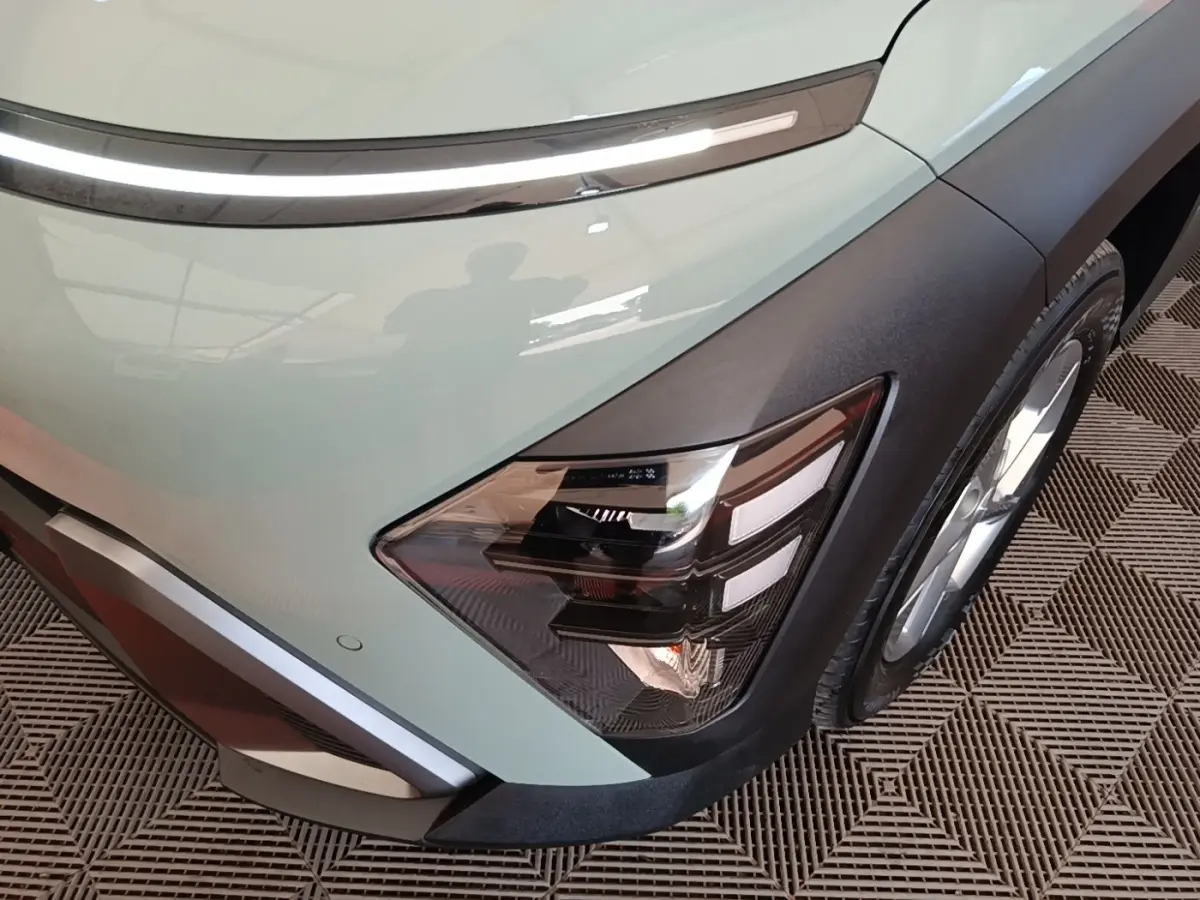 Gros plan sur l'avant droit vert du Hyundai Kona 2024, mettant en valeur le phare LED et la roue.