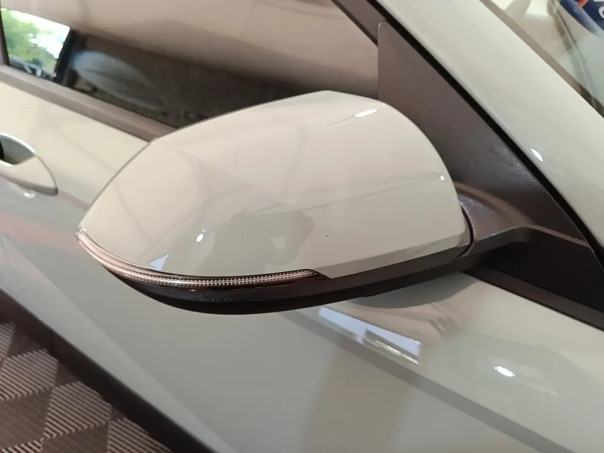 Gros plan sur le rétroviseur droit blanc du Hyundai Kona 1.6 Hybrid 2024 avec clignotant intégré.