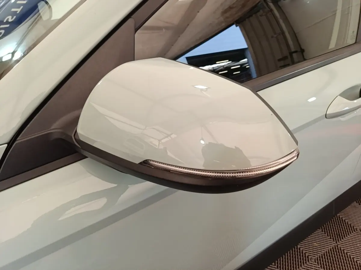 Gros plan sur le rétroviseur droit blanc du Hyundai Kona 2024 hybride, avec clignotant intégré visible.