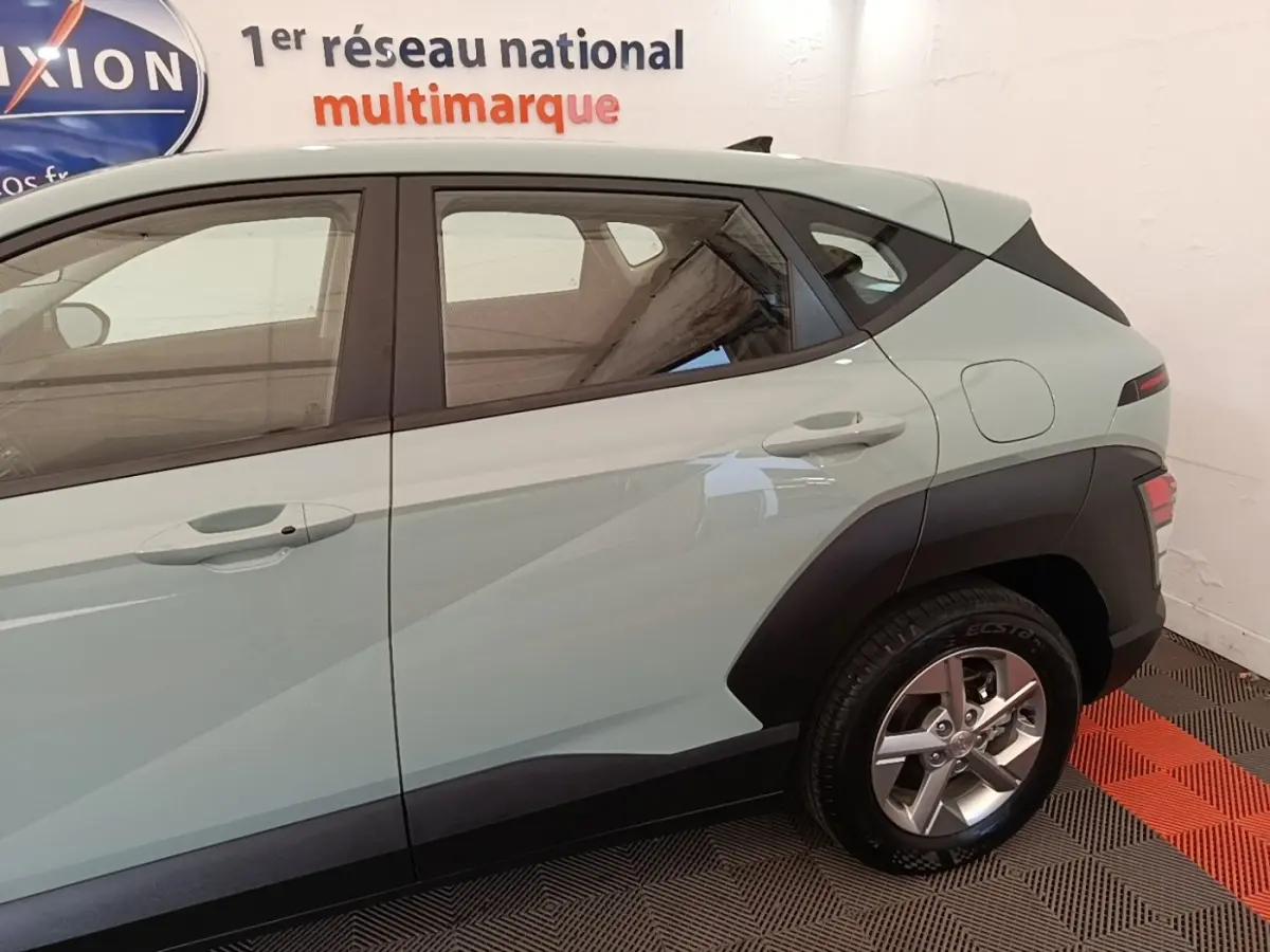 Vue latérale droite d’un Hyundai Kona 2024 vert avec jantes alliage et protections noires sur les ailes.
