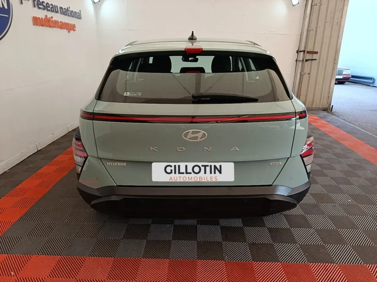 Vue arrière d'une Hyundai Kona hybride 2024 vert clair avec feux arrière LED en bandeau et logo central.