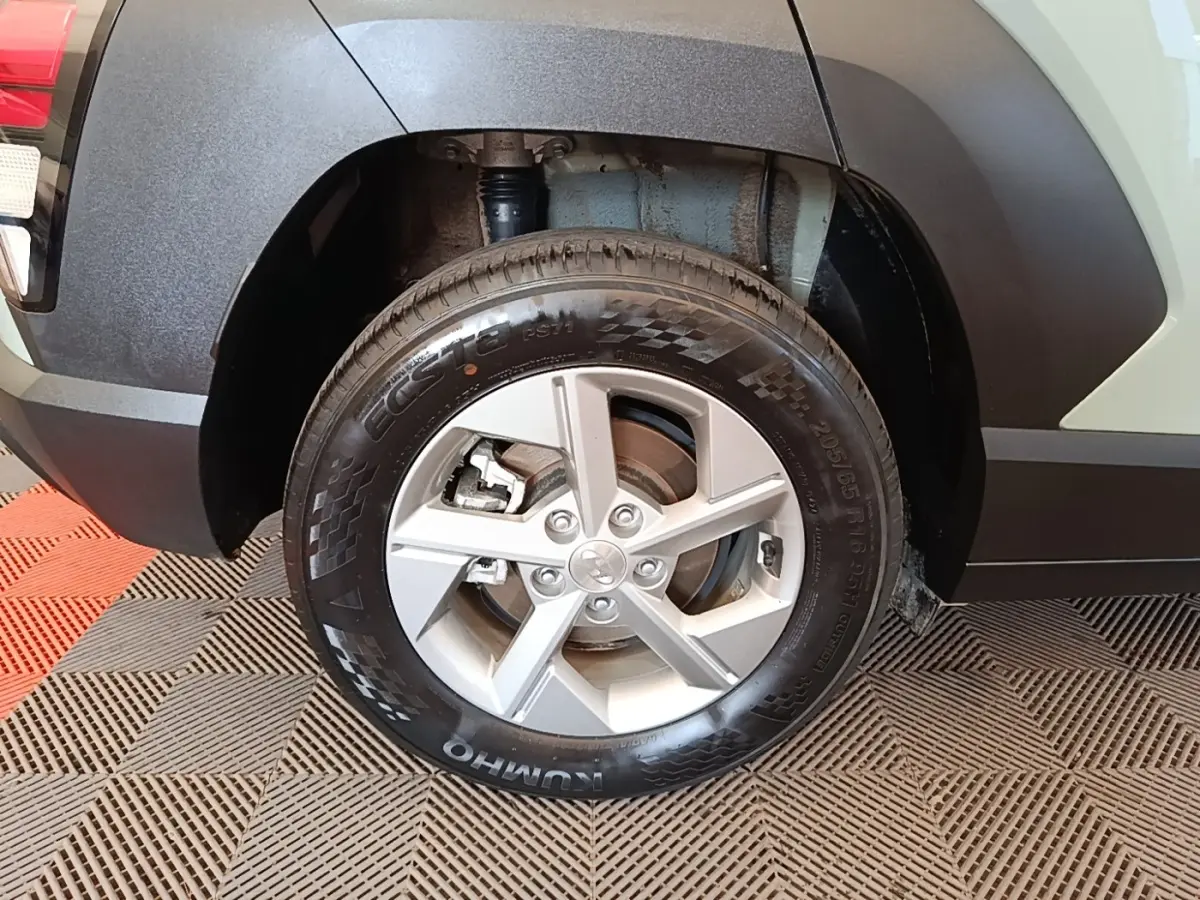 Gros plan sur la roue arrière droite d’un Hyundai Kona vert 2024 avec jante alliage argent et passage de roue noir.