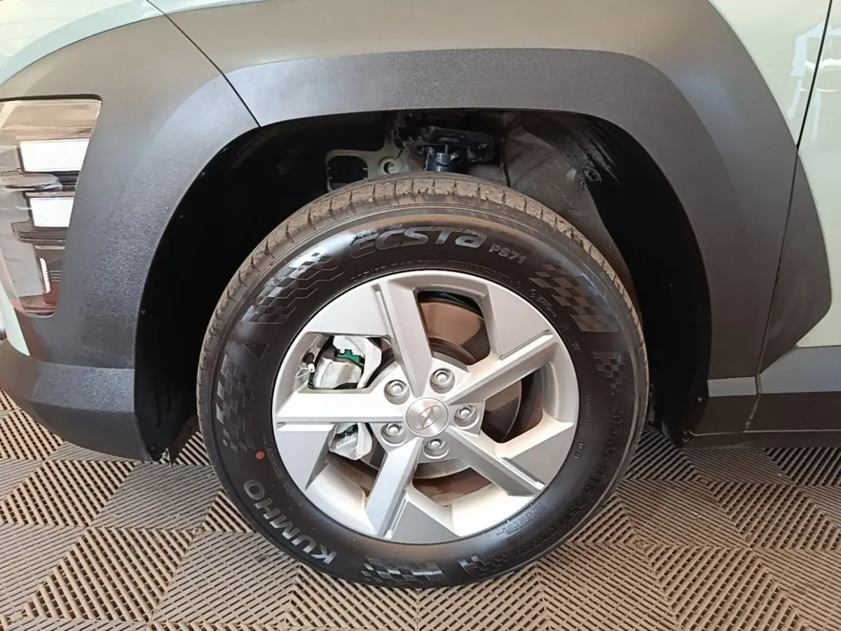 Gros plan sur la roue avant droite d'une Hyundai Kona 2024 verte, avec jante alliage et passage de roue noir mat.