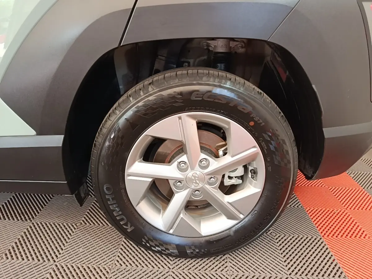 Gros plan sur la roue avant droite du Hyundai Kona vert 2024 avec jante alliage et pneu Kumho Ecsta.