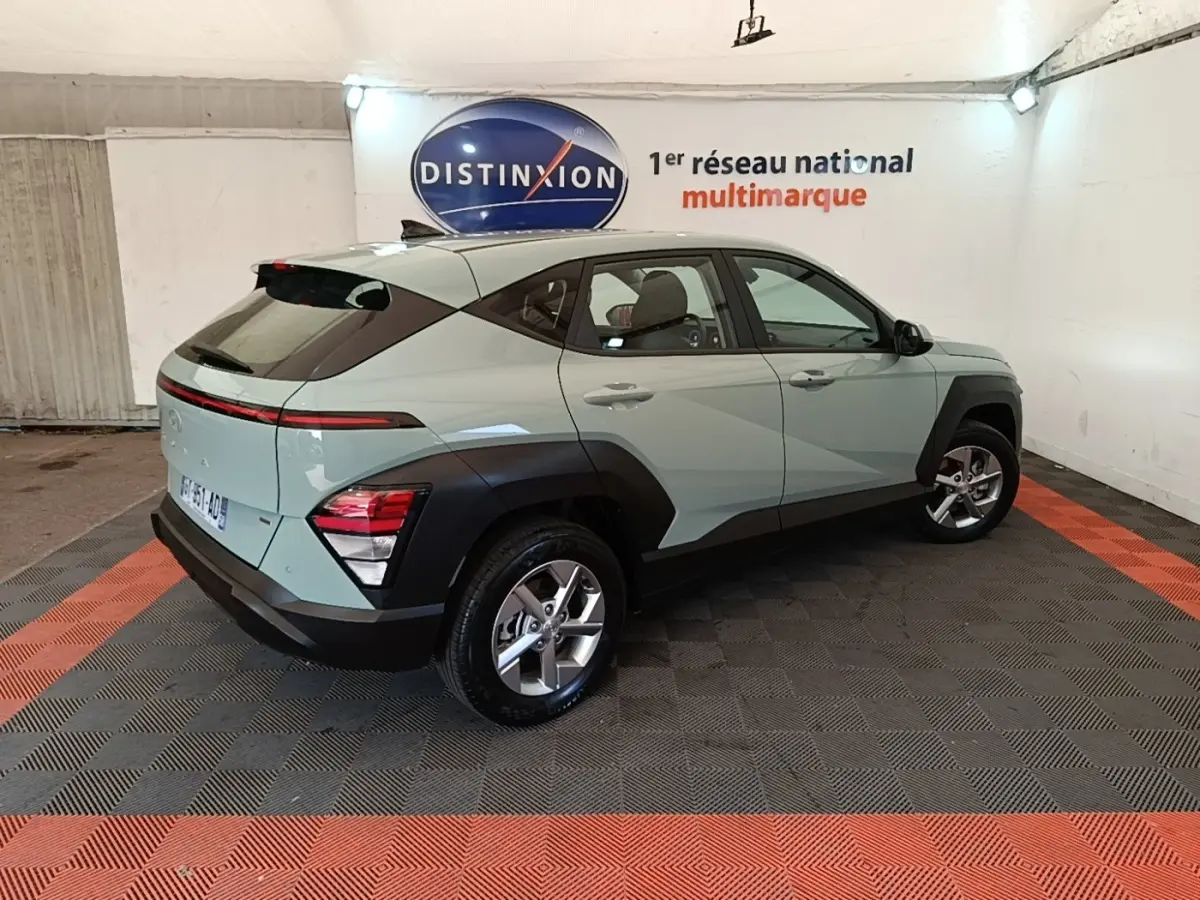 Vue 3/4 arrière droite d'un Hyundai Kona 2024 vert avec arches noires et feux arrière LED fins.