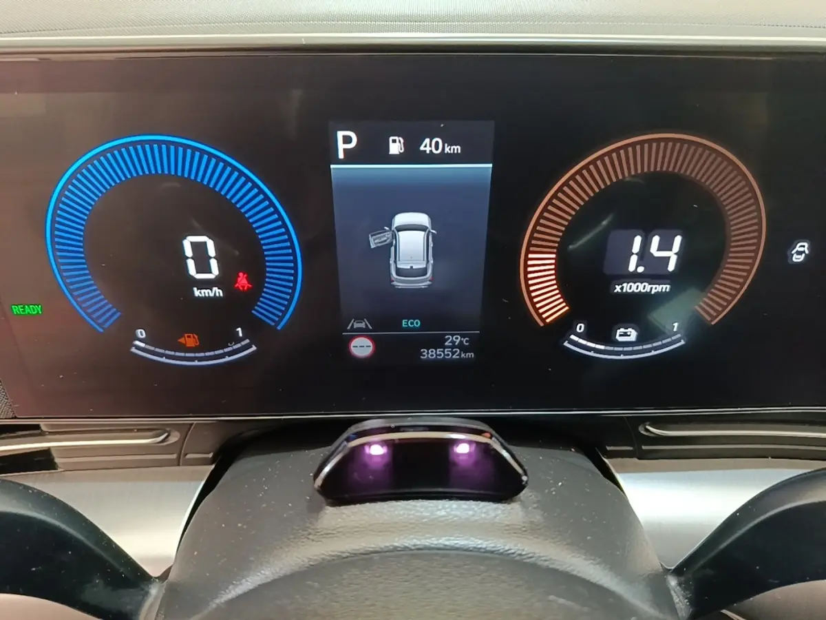 Tableau de bord numérique du Hyundai Kona 2024, affichage vitesse, régime moteur et porte ouverte côté gauche.