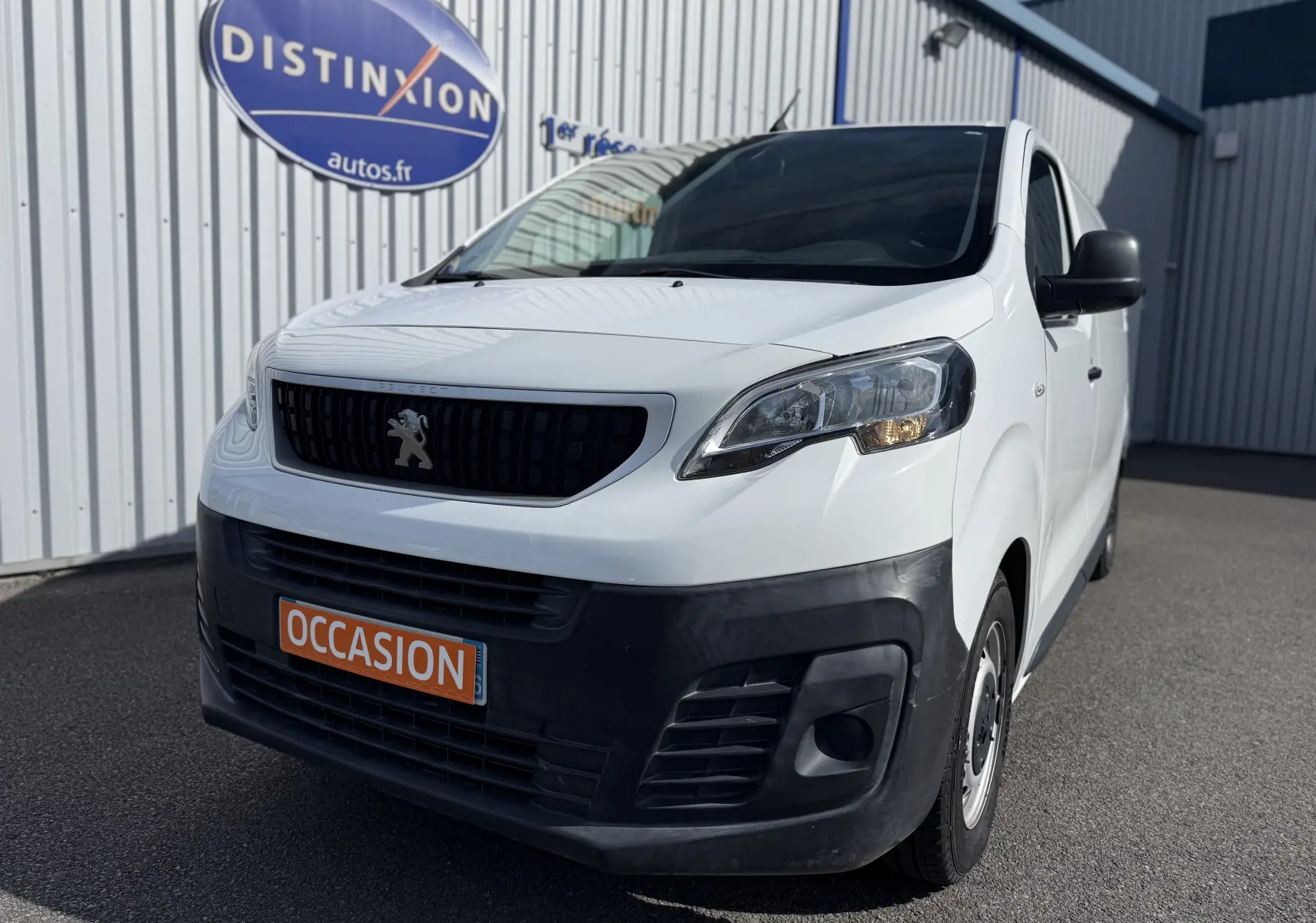 Vue 3/4 avant droite d’un Peugeot Expert FGN blanc de 2017 avec pare-chocs noir et plaque "OCCASION" orange.