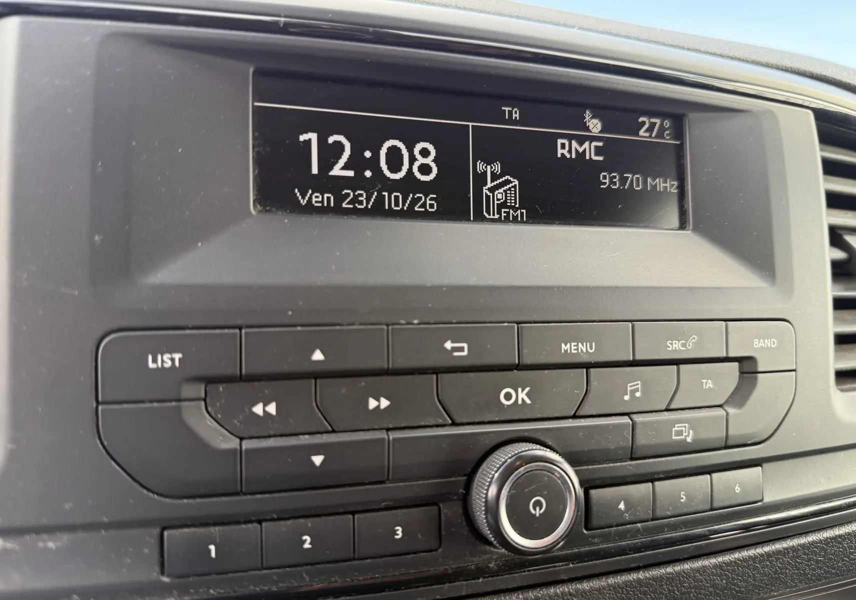 Gros plan sur l’autoradio noir du Peugeot Expert FGN 2017 affichant l’heure, la radio RMC et la température intérieure.