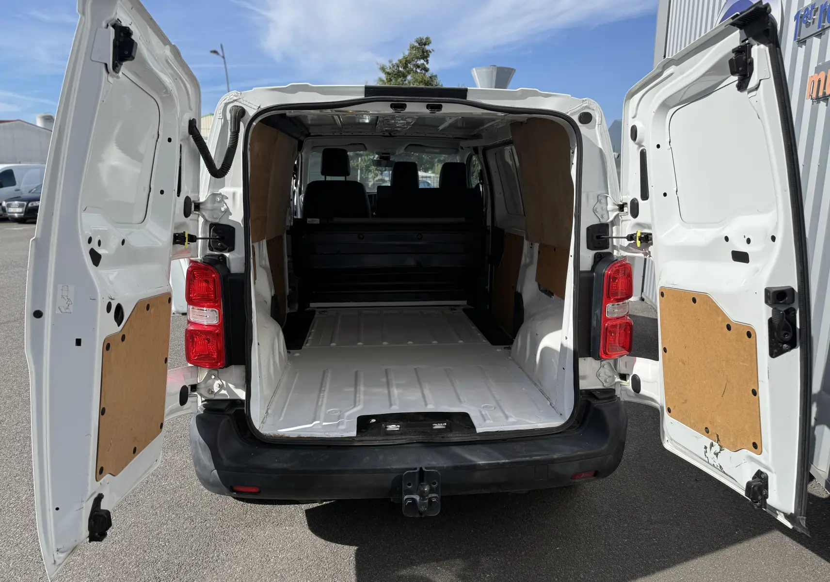 Vue arrière du Peugeot Expert FGN blanc 2017 avec portes ouvertes montrant l'espace de chargement vide et les panneaux en bois.