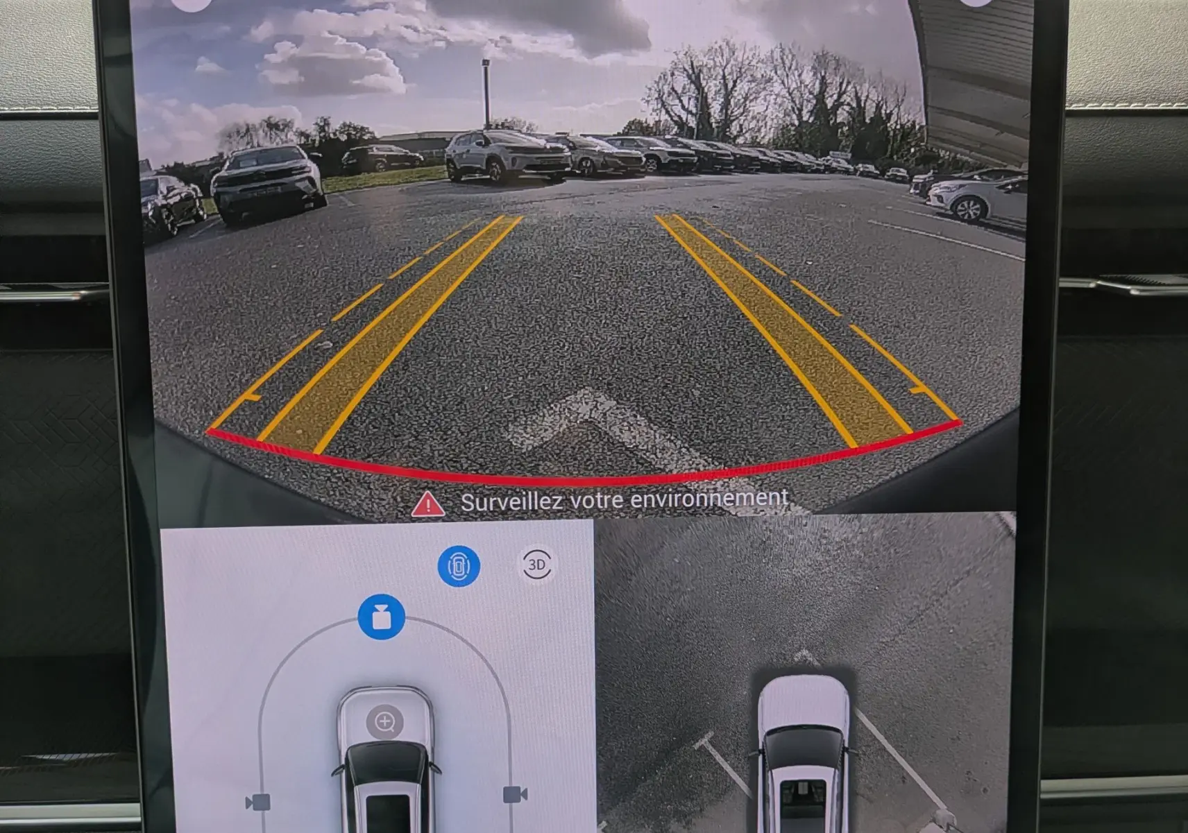 Écran intérieur montrant la caméra de recul et vue 360° du JAECOO J7 olive gris métal avec toit noir en stationnement.