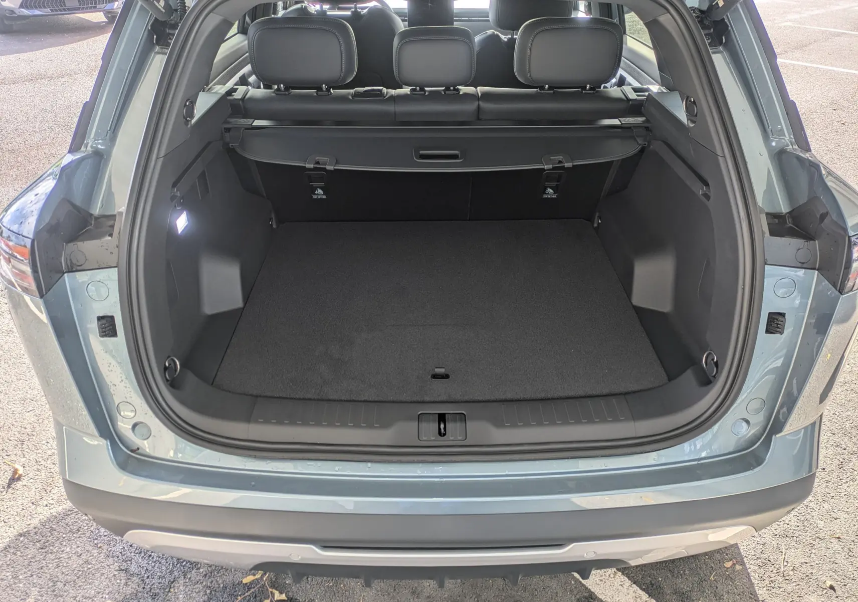 Coffre ouvert vu de l'arrière d'un JAECOO J7 olive grey metal, montrant un espace de chargement spacieux et noir.