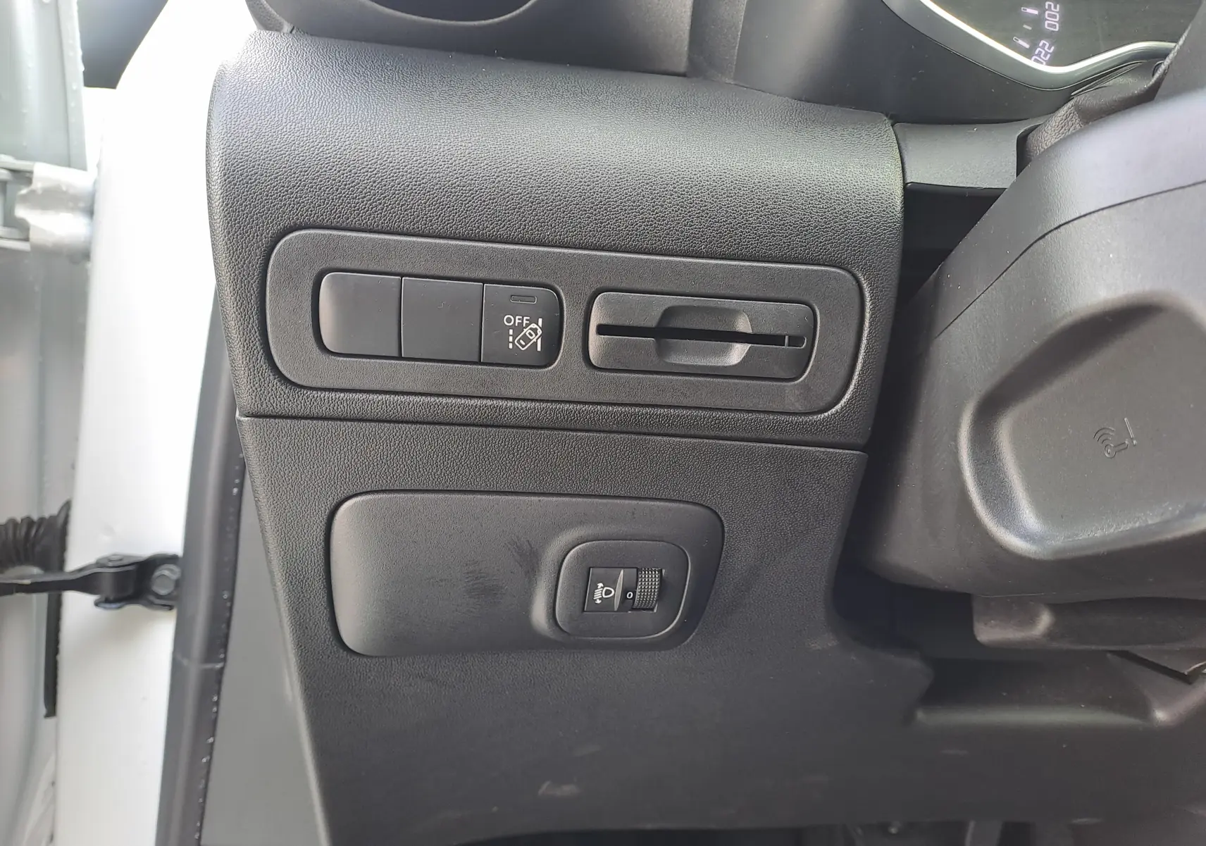 Vue rapprochée des commandes de réglage d'éclairage et d'assistance sur le côté gauche du tableau de bord d'une Citroën C3 Aircross blanc banquise 2024.