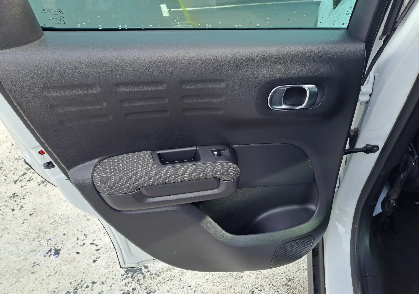 Vue intérieure de la porte arrière droite noire avec accoudoir tissu gris du Citroën C3 Aircross blanc banquise 2024