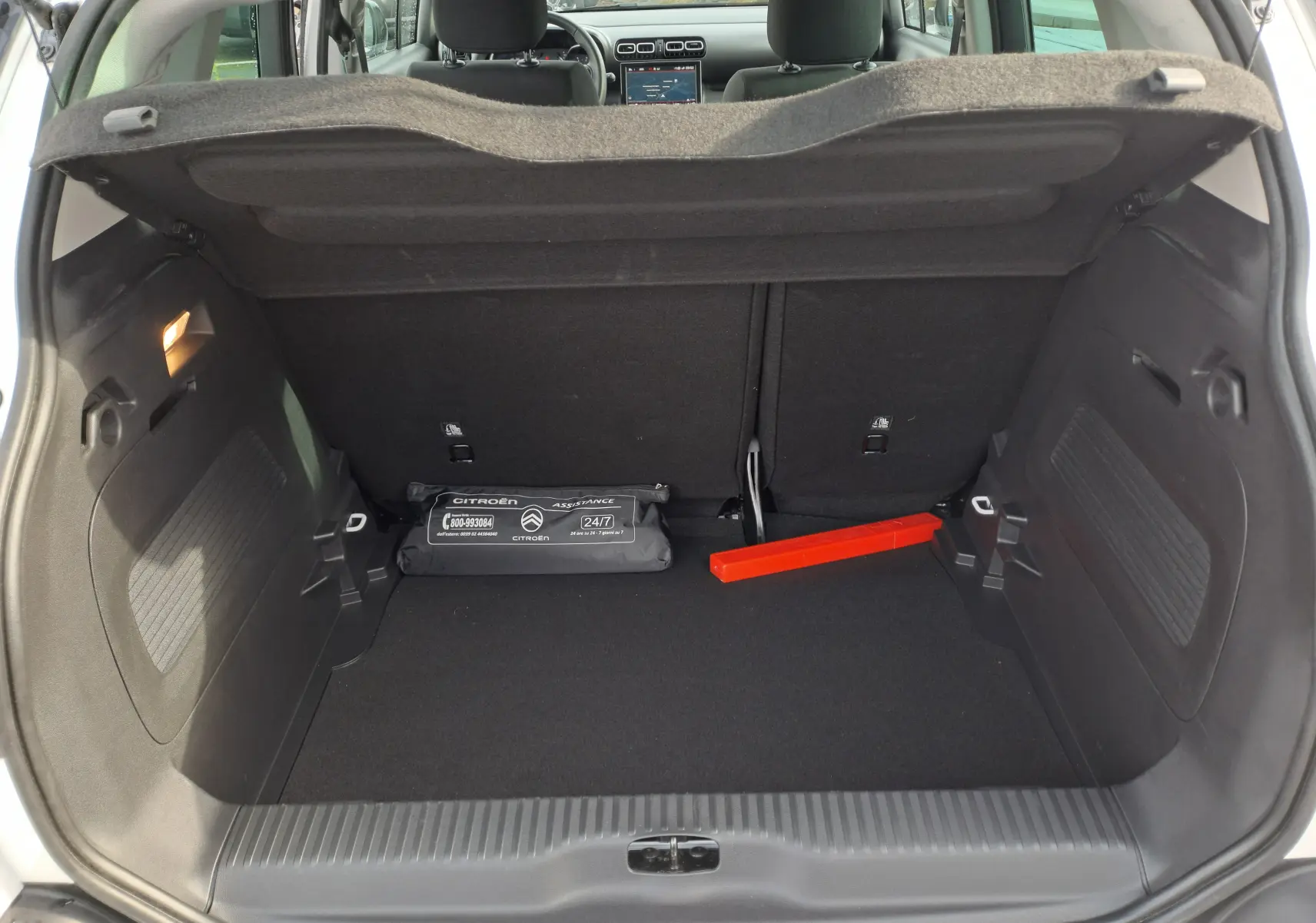 Coffre ouvert d'une Citroën C3 Aircross blanc banquise, montrant un triangle de signalisation rouge et une trousse de secours noire.