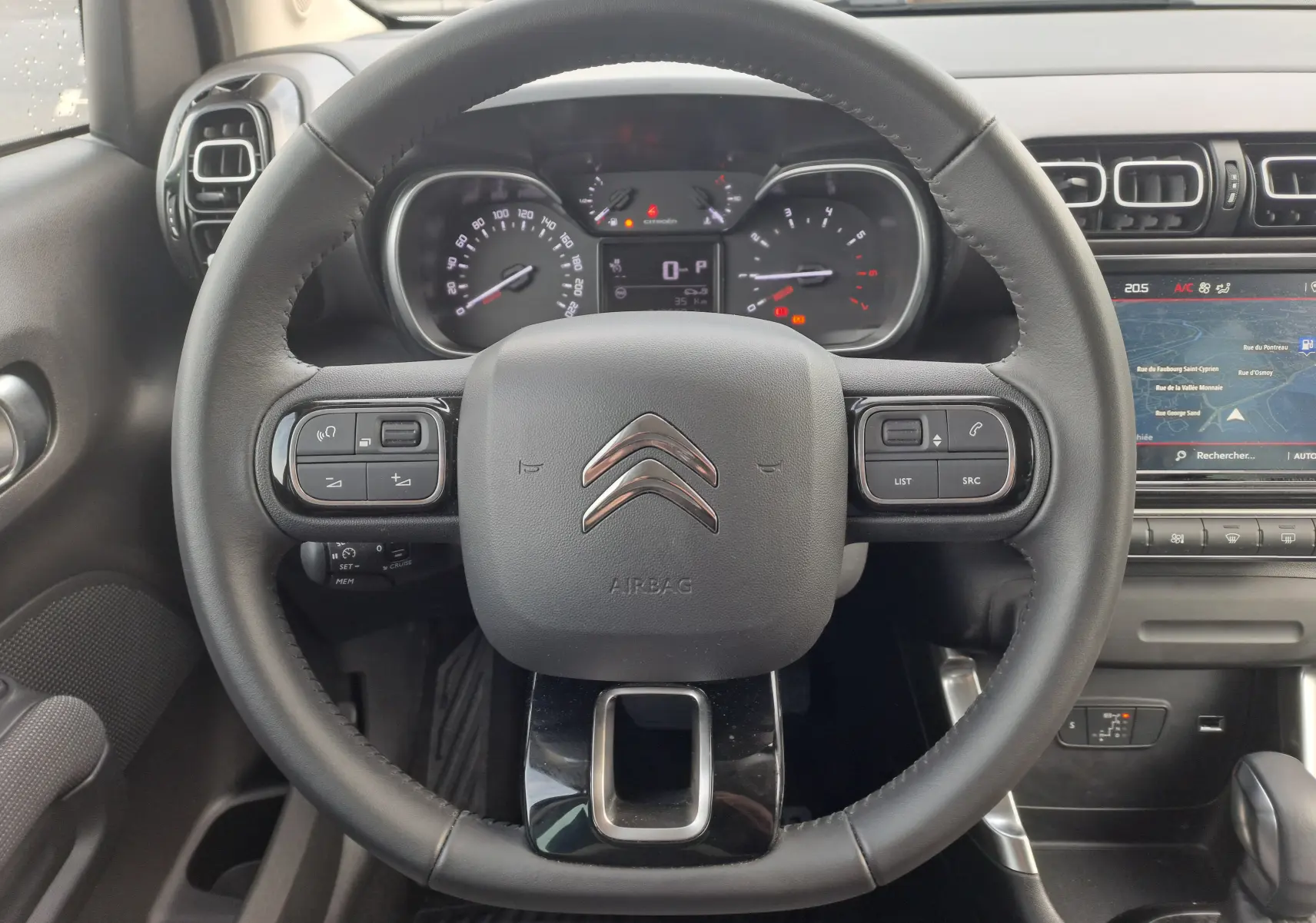 Vue rapprochée du volant noir de la Citroën C3 Aircross 2024 avec tableau de bord et écran tactile visible.