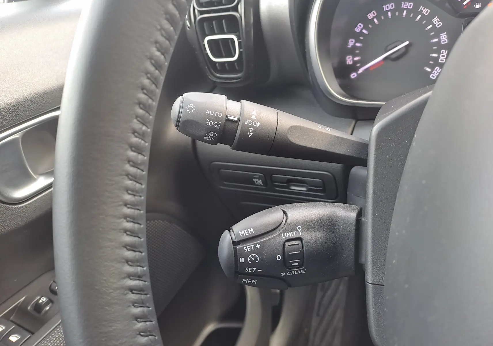 Gros plan sur les commandes au volant du Citroën C3 Aircross 2024, montrant les leviers de clignotants et régulateur de vitesse.