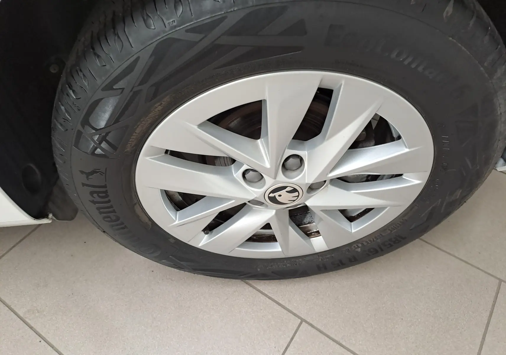 Gros plan sur la roue avant gauche d'une Skoda Fabia blanche 2023 avec jante en alliage et logo Skoda central.