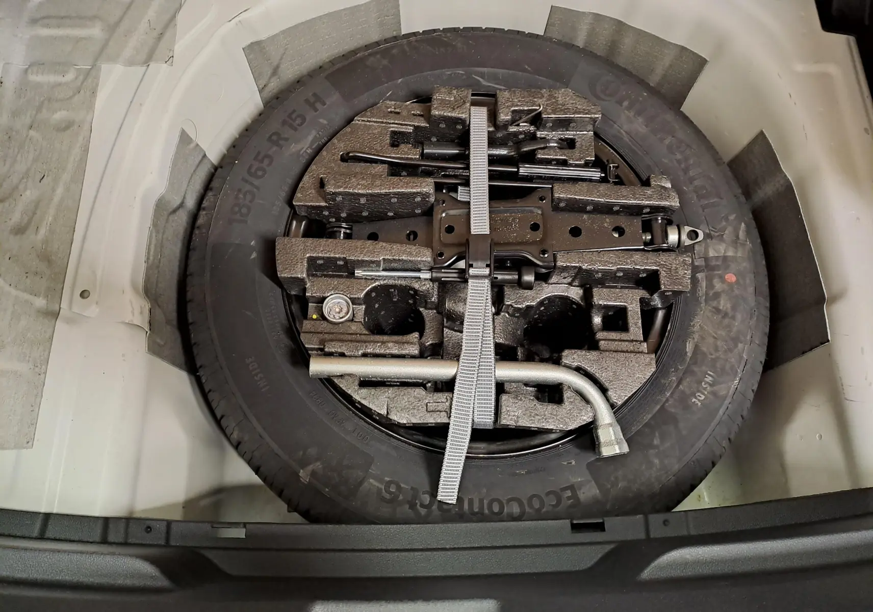 Vue plongeante sur la roue de secours et les outils de bord dans le coffre d'une Skoda Fabia Blanc Candy 2023.