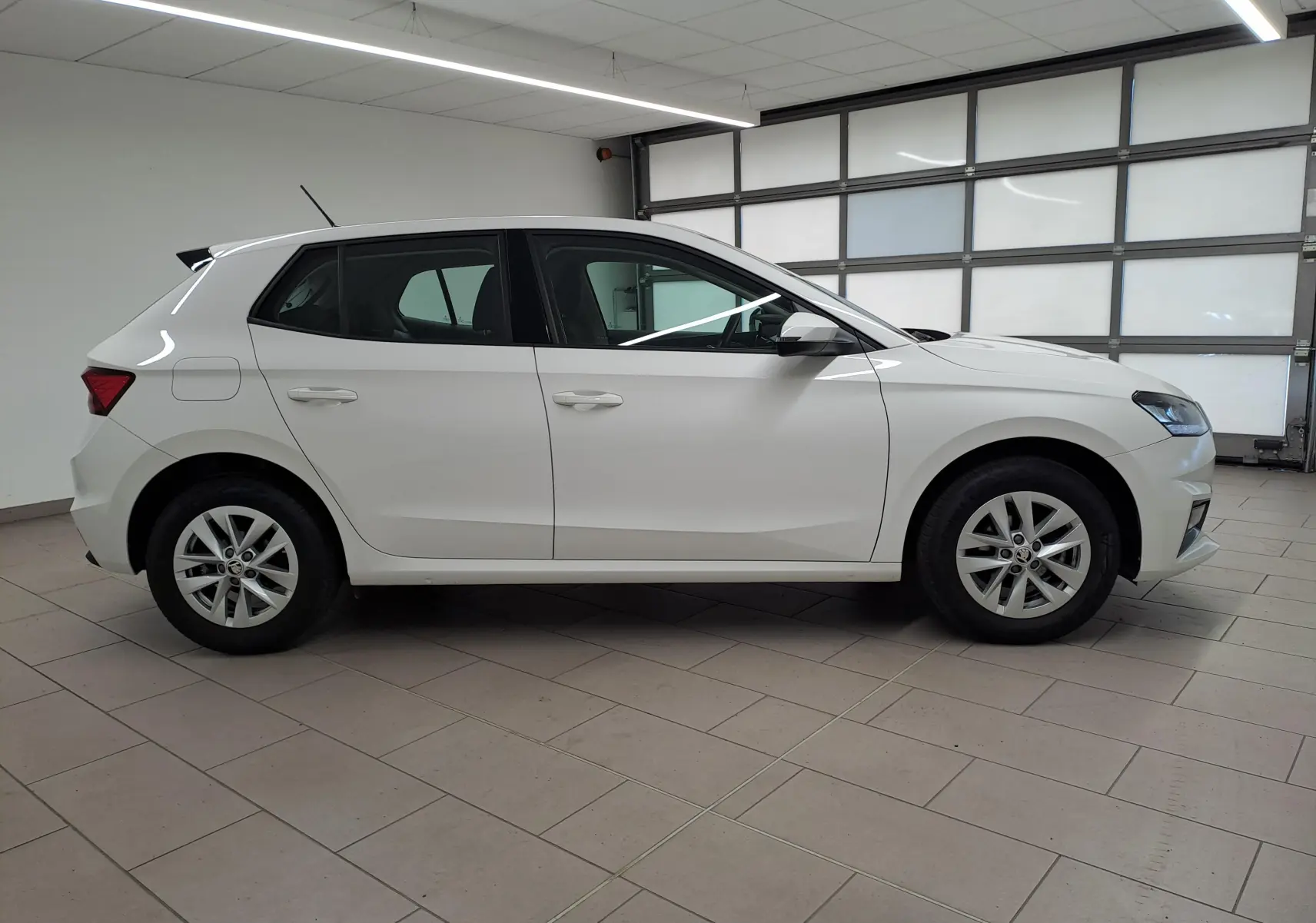 SKODA FABIA 2023 blanc candy vue de profil côté gauche dans un garage avec jantes alliage simples.