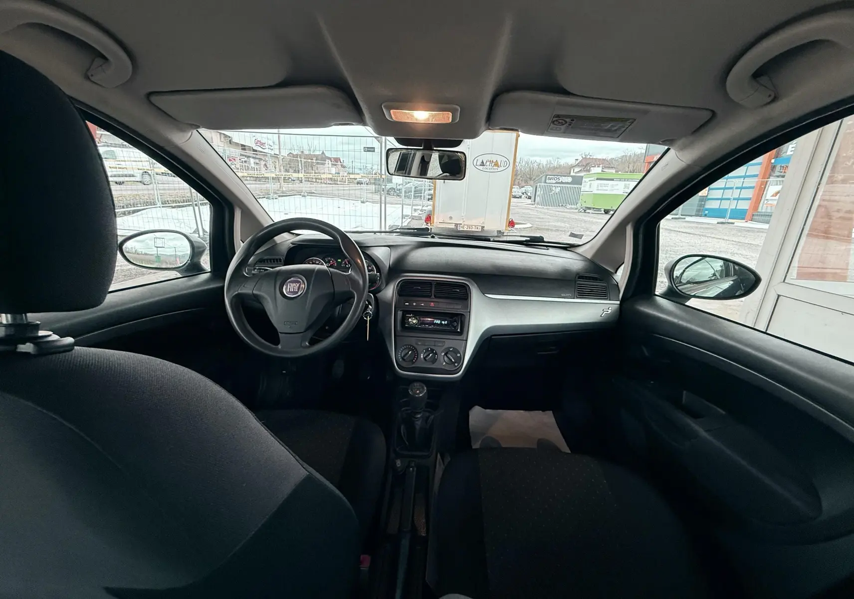 Vue intérieure avant de la Fiat Punto noire 2009 montrant le tableau de bord et le volant avec boîte manuelle.