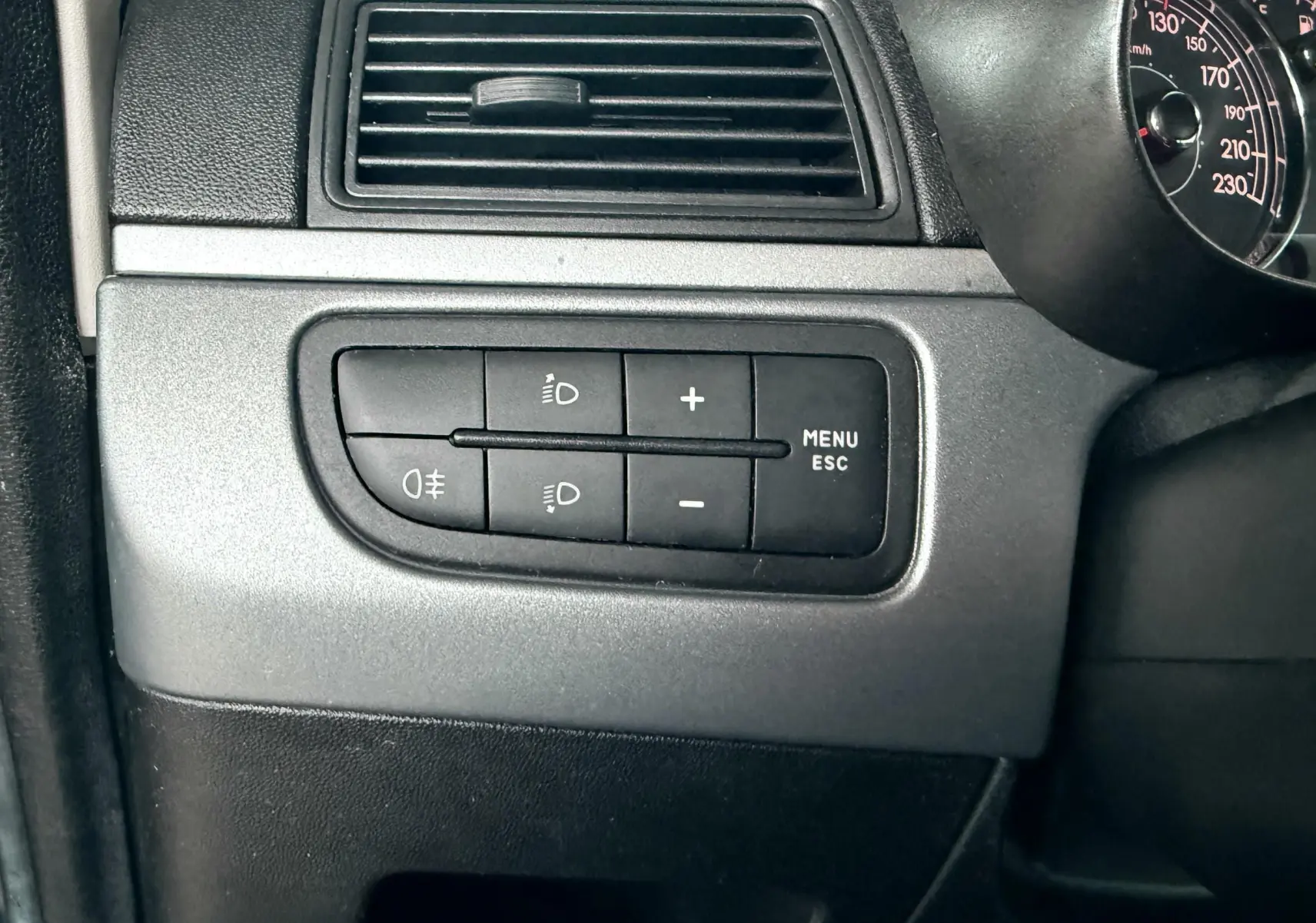 Gros plan sur les commandes d’éclairage et le tableau de bord partiel d’une Fiat Punto noire de 2009.