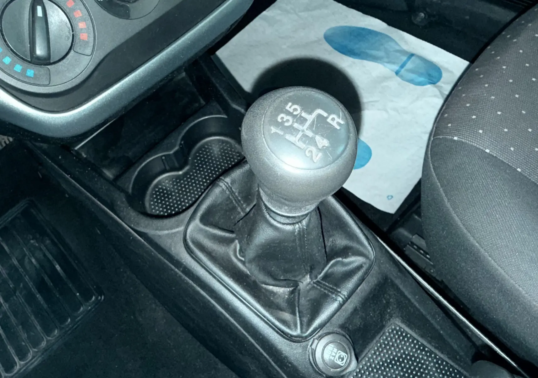 Gros plan sur la commande de boîte manuelle noire de la Fiat Punto 1.2 i 65, avec partie centrale et siège passager visibles.