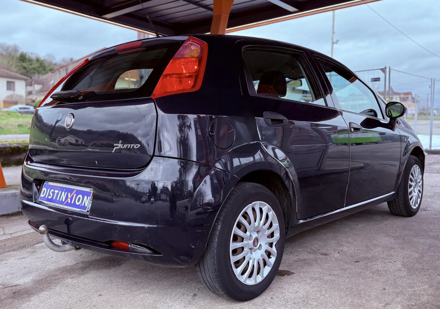 Vue 3/4 arrière droite d'une Fiat Punto noire de 2009 avec attelage et jantes multibranches argentées.