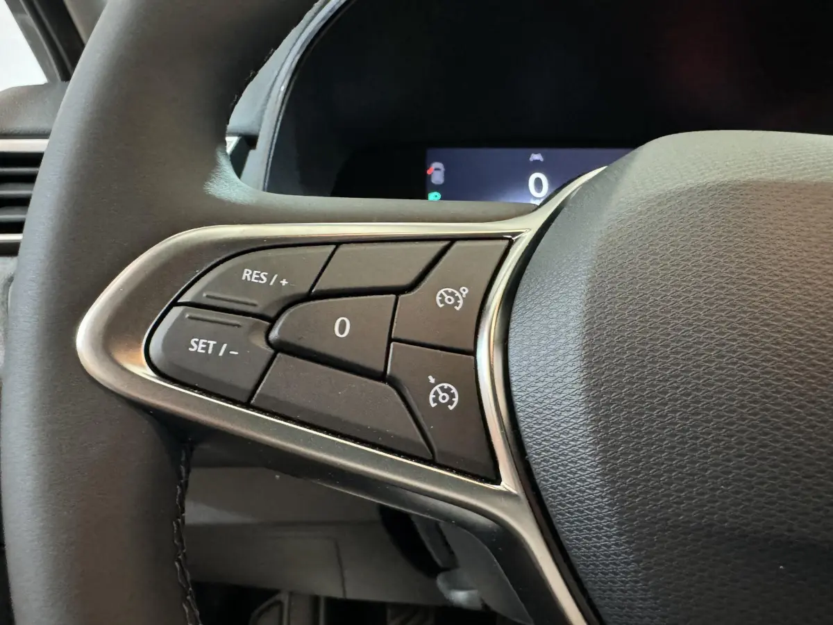 Gros plan sur les commandes du régulateur de vitesse au volant cuir de la Renault Clio gris clair Evolution Blue dCi 100 2025.