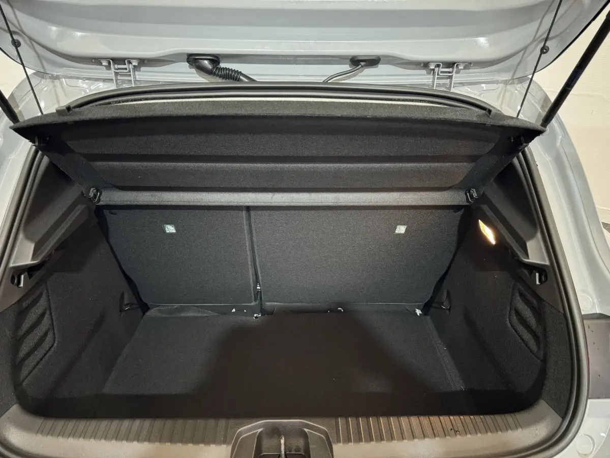 Coffre ouvert vu de l'arrière d'une Renault Clio gris clair 2025, montrant l'espace de chargement et la tablette de coffre.