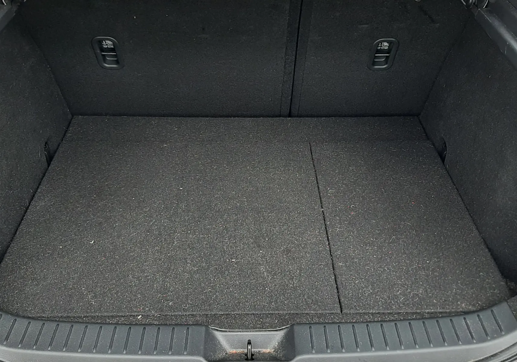 Vue du coffre ouvert d'une Mazda CX-30 blanche, montrant un espace de chargement propre et tapissé en noir.