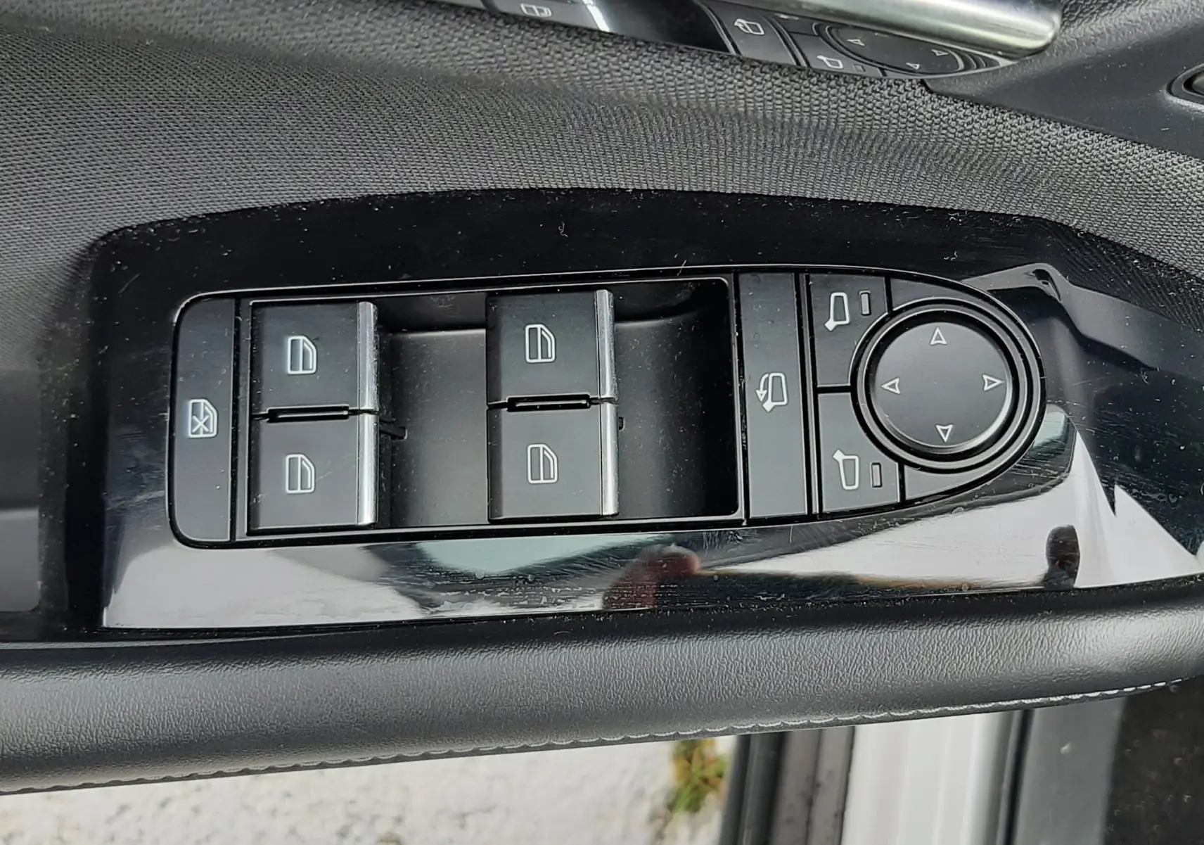 Gros plan sur les commandes des vitres et rétroviseurs côté conducteur d’un Mazda CX-30 2024 blanc céramique.